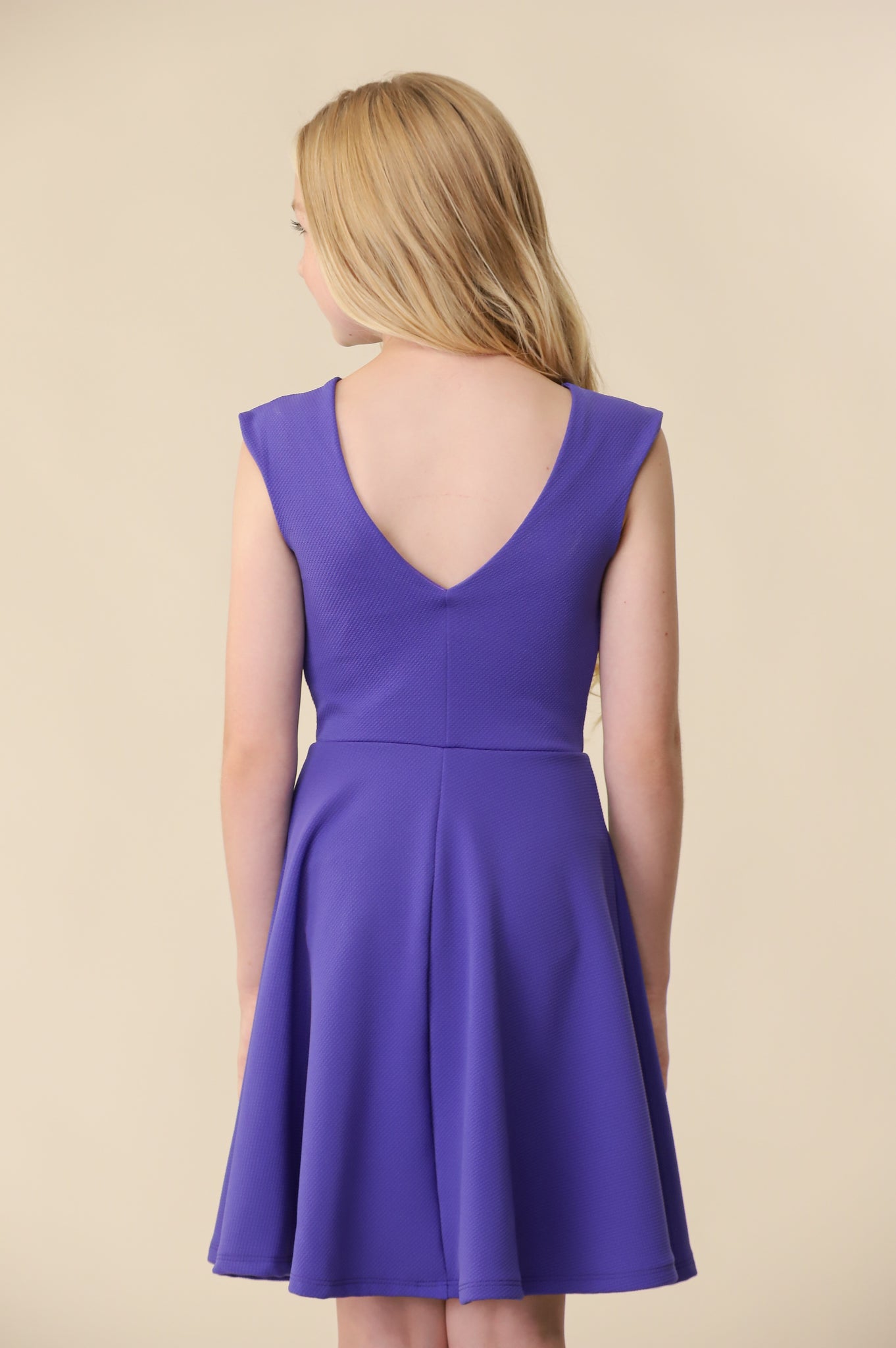 The cap sleeve textured fit and flare dress is shown in royal blue with high neck line, shoulder coverage and lower v-back detailing for a chic and sophisticated look. This dress can be worn to a more coservative special occasion event like cotillion, graduation, or religious service like a bat mitzvah service or church ceremony.