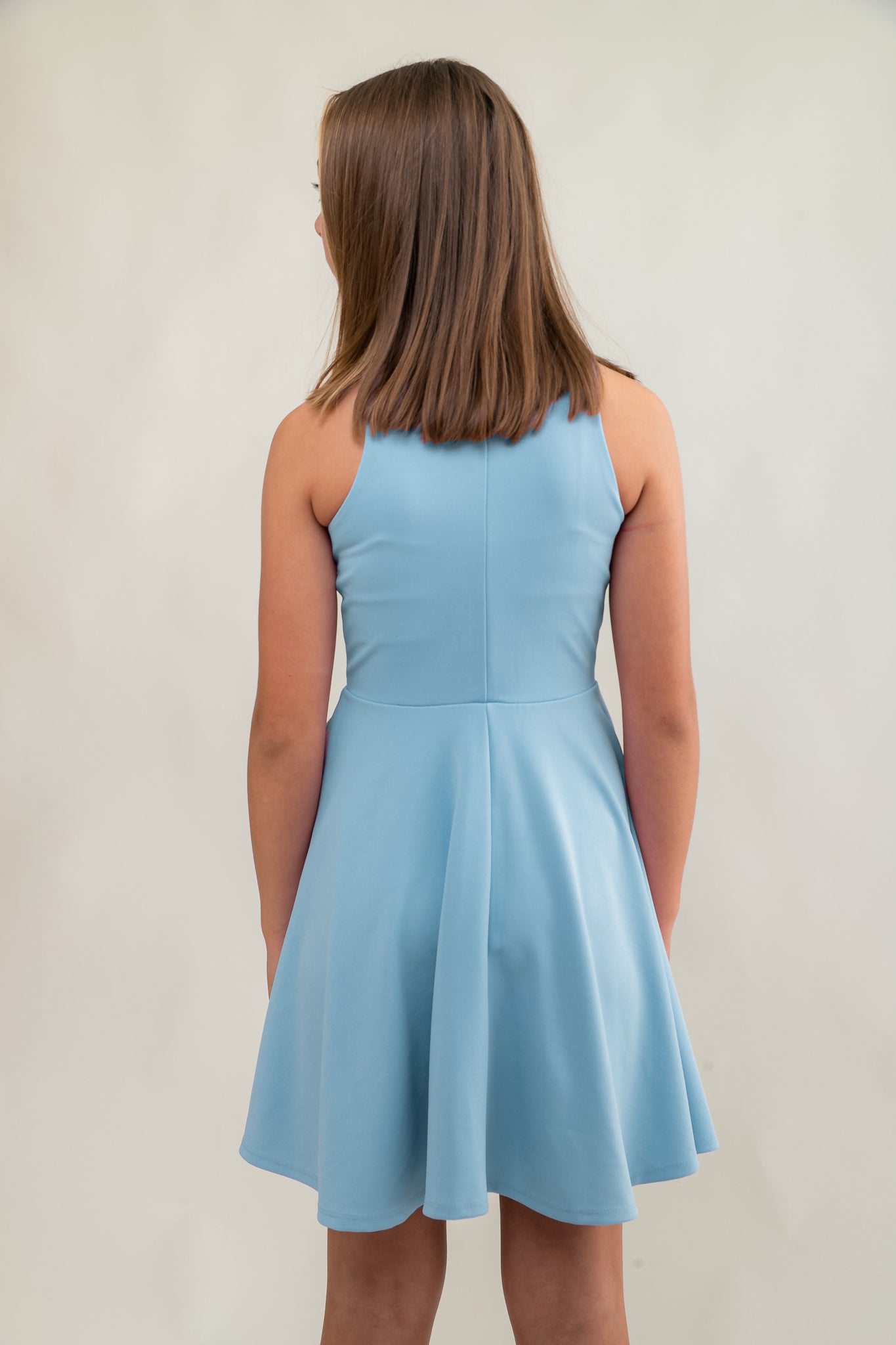 The tank style sleeve textured fit and flare dress is shown in light blue with high neck line, racerback detailing and dart bodice for a chic and sophisticated look. This dress can be worn to a more conservative special occasion event like cotillion, graduation, or religious service like a bat mitzvah service or church ceremony.