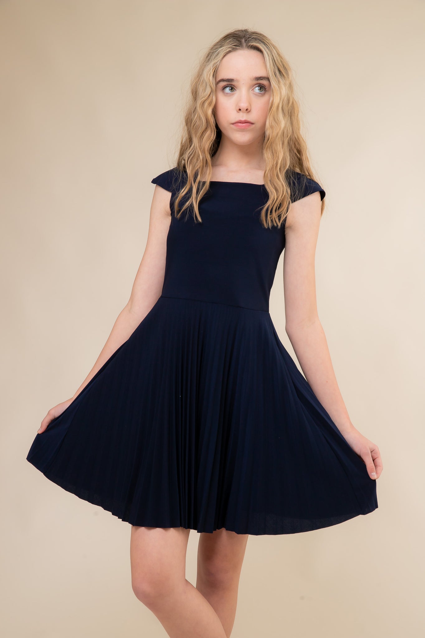 Cap sleeve pleated skirt in navy with all over stretch fabric, cap sleeve detailing for shoulder coverage and hits above the knee.