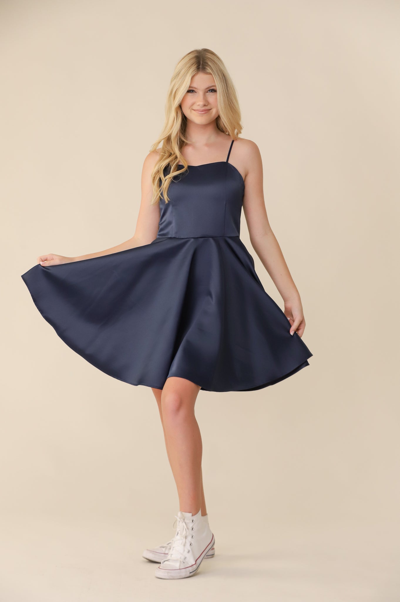 Blonde girl in a Un Deux Trois fit and flare navy satin dress.