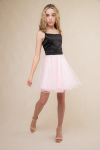 A young blonde haired girl in the fit and flare black satin bodice dress with pink tulle skirt and hem. 