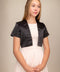 Blonde girl in a black satin bolero jacket worn over a dress.