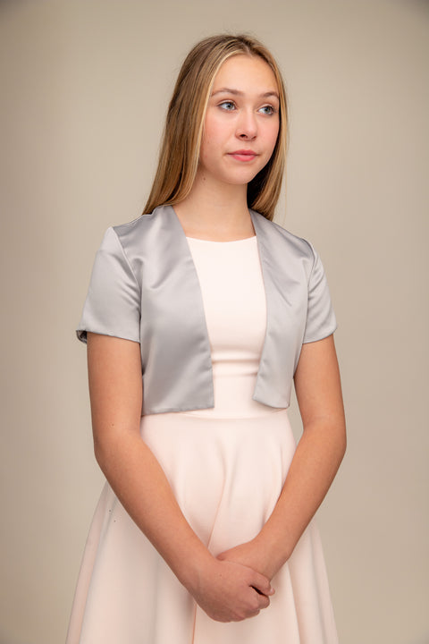 Blonde girl in a silver satin bolero jacket worn over a dress.