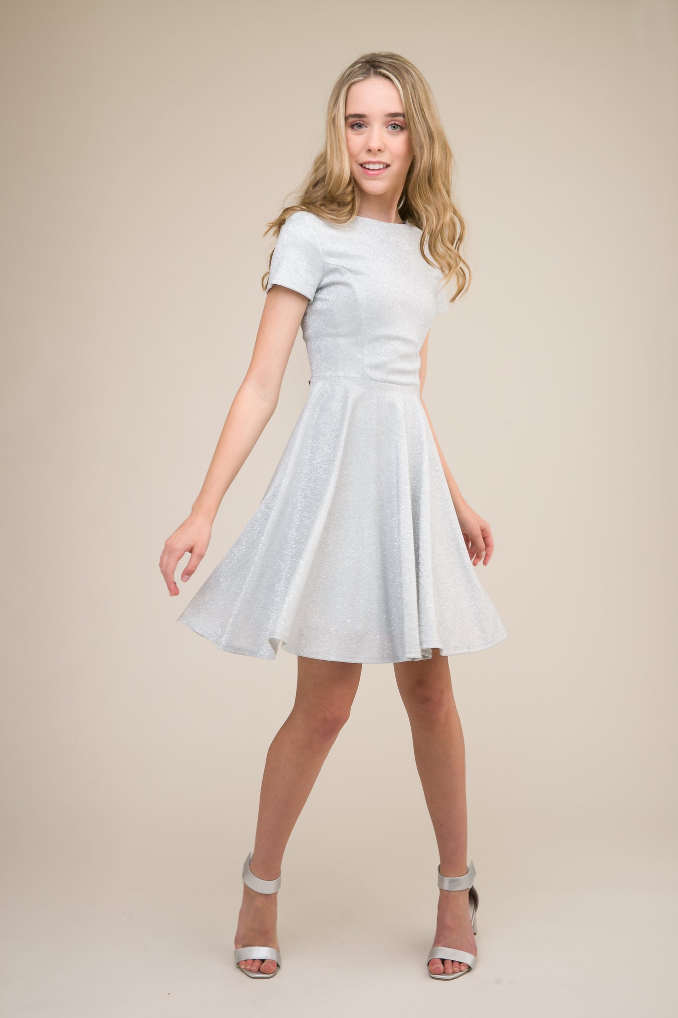 This is an all over silver stretch glitter dress made with soft lining. It's non-scratch fabric is a perfect dress that hits right above the knee and has a lower v-back detailing.