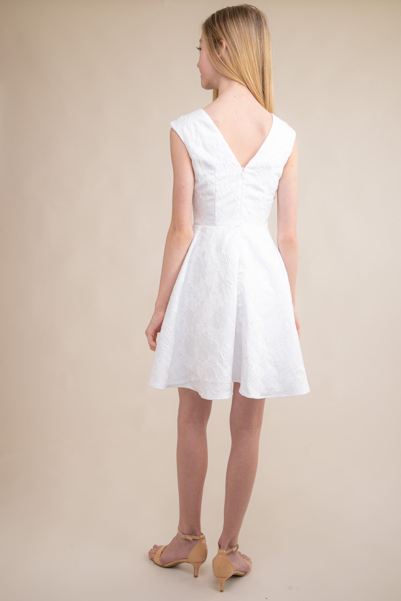 This is an all over jacquard, cap sleeve dress in white with non-stretch material, zipper back, and longer length detailing. This dress is perfect for any religious event like bat mitzvah, cotillion or church service.